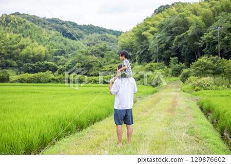 Father and son on shoulders, back view, summer vacation in the countryside 129876602