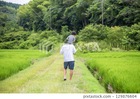 Father and son on shoulders, back view, summer vacation in the countryside 129876604