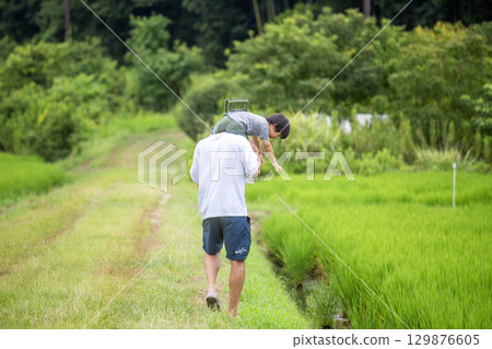 Father and son on shoulders, back view, summer vacation in the countryside 129876605