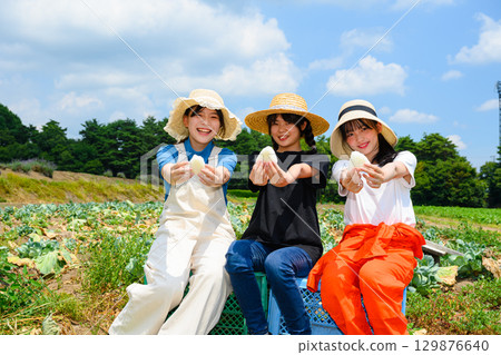 Japanese girls wearing straw hats sit holding white rice balls on a summer plateau Japanese girls wearing straw hats sit holding white rice balls on a summer plateau 129876640
