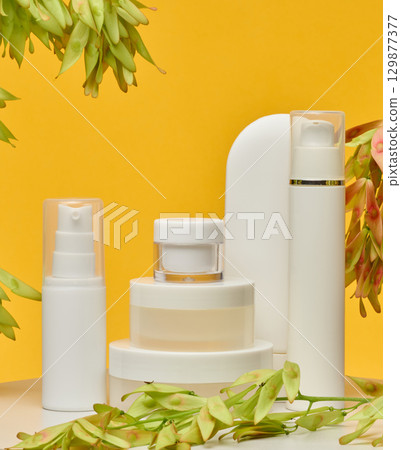 Set of white plastic cosmetic packaging without brand on yellow background. Container for beauty industry, skin care and advertising Set of white plastic cosmetic packaging without brand on yellow background. Container for beauty industry, skin care and advertising 129877377