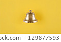 Metal bell over yellow background 129877593