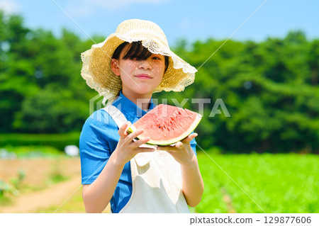 夏日高原上，戴著草帽的小學生手持西瓜的場景 129877606