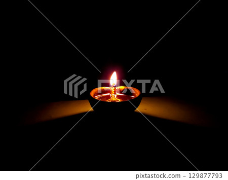 Single Clay Oil Lamp Glowing in Darkness Single Clay Oil Lamp Glowing in Darkness 129877793