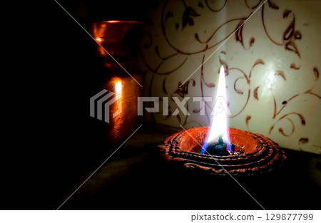 Single Clay Oil Lamp Glowing in Darkness Single Clay Oil Lamp Glowing in Darkness 129877799