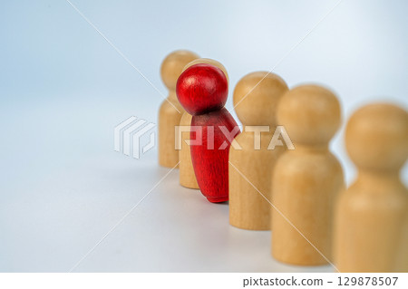 A red wooden figure stand before beige figures, symbolizing collective voices against silence in leadership, bullying, or harassment. A red wooden figure stand before beige figures, symbolizing collective voices against silence in leadership, bullying, or harassment. 129878507