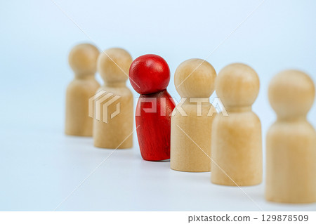 A red wooden figure confronts beige figures, symbolizing the power of one voice against group silence in leadership, bullying, or harassment. A red wooden figure confronts beige figures, symbolizing the power of one voice against group silence in leadership, bullying, or harassment. 129878509
