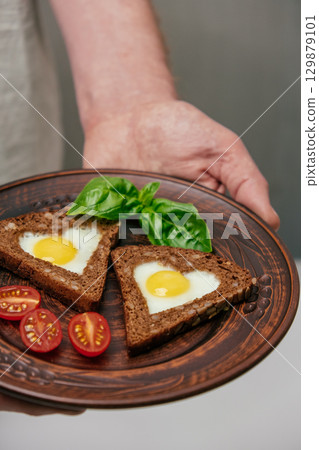 delicious breakfast feature eggs in toast served cherry tomatoes, basil on rustic plate. closeup. 129879101