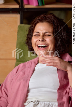Brunette woman laughing with open mouth in cheerful mood Brunette woman laughing with open mouth in cheerful mood 129879376