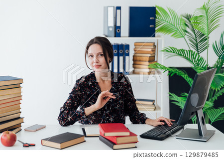 A professional employee is seen deeply engaged with his tasks, writing notes beside her laptop. 129879485