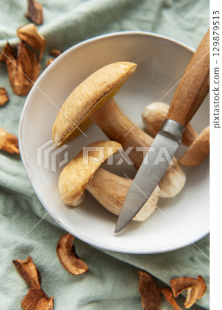 Fresh mushrooms with knife in bowl preparing for cooking Fresh mushrooms with knife in bowl preparing for cooking 129879513