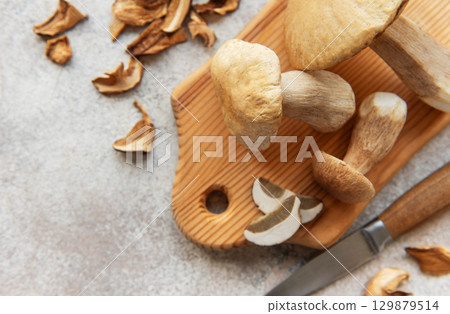 Fresh penny bun mushrooms on cutting board with knife and dried slices 129879514