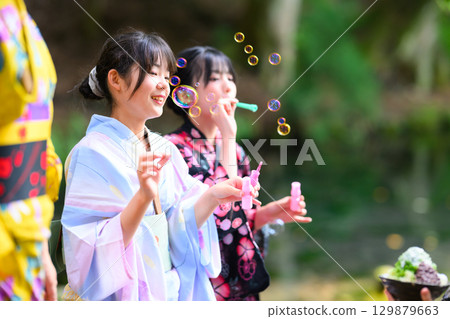 A summer scene of a Japanese elementary school girl wearing a yukata playing with soap bubbles A summer scene of a Japanese elementary school girl wearing a yukata playing with soap bubbles 129879663