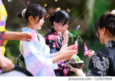 A summer scene of a Japanese elementary school girl wearing a yukata playing with soap bubbles 129879664