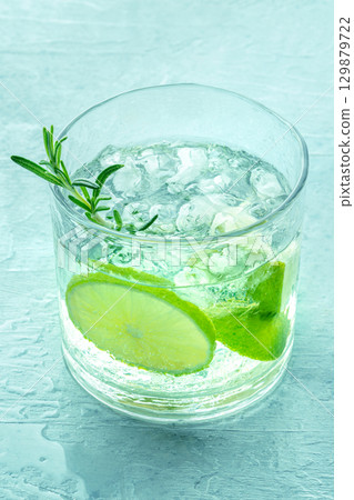 Gin tonic, a glass of gin with soda, lime, rosemary, and ice, on blue Gin tonic, a glass of gin with soda, lime, rosemary, and ice, on blue 129879722
