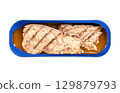 Grilled mackerel fillet, in its own juice, in an opened tin can. Salted piece of mackerel, fried on a grill, preserved in the liquid that naturally extracts from the fish during the canning process. 129879793