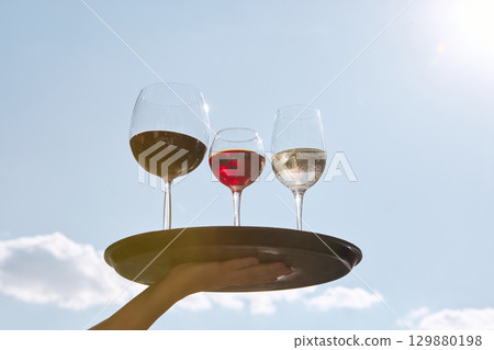 Red white and rose wine glasses on tray against blue sky Red white and rose wine glasses on tray against blue sky 129880198