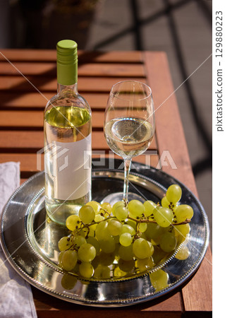 White wine bottle with blank label with grapes and glass on wooden table White wine bottle with blank label with grapes and glass on wooden table 129880223