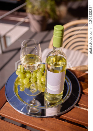 Bottle of white wine with blank label, with grapes on silver tray, mockup for ad, text Bottle of white wine with blank label, with grapes on silver tray, mockup for ad, text 129880224