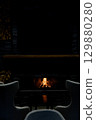 Cozy living room with a modern stone fireplace, warm flames flickering inside, creating an inviting and tranquil atmosphere. 129880280