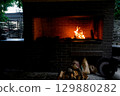 Cozy living room with a modern stone fireplace, warm flames flickering inside, creating an inviting and tranquil atmosphere. 129880282