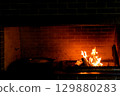 Cozy living room with a modern stone fireplace, warm flames flickering inside, creating an inviting and tranquil atmosphere. 129880283