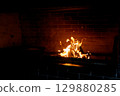 Cozy living room with a modern stone fireplace, warm flames flickering inside, creating an inviting and tranquil atmosphere. 129880285