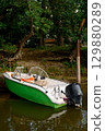 Motorboat on the river bank. Boat in the water against the background of the forest in sunny weather. 129880289