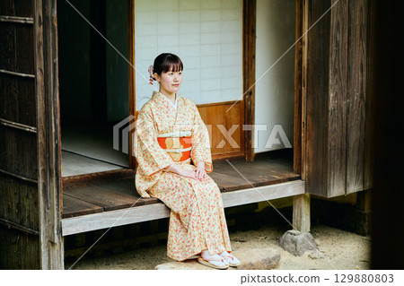 A woman in a kimono quietly standing on the veranda 129880803