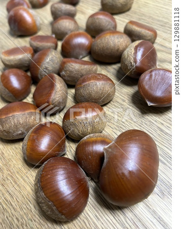 A lot of chestnuts spread out on a wooden table A lot of chestnuts spread out on a wooden table 129881118