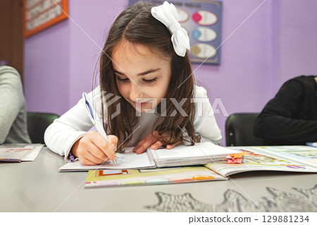Schoolgirl writing an assignment at language school class 129881234