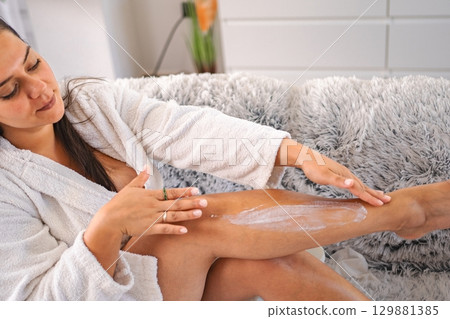 Woman applying moisturizing cream on her legs after shower Woman applying moisturizing cream on her legs after shower 129881385