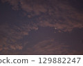 Minimalist view of a crescent moon surrounded by textured clouds at twilight. The soft gradient sky creates a calm, atmospheric mood with copy space. 129882247
