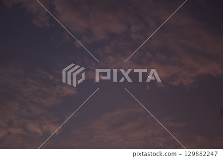 Minimalist view of a crescent moon surrounded by textured clouds at twilight. The soft gradient sky creates a calm, atmospheric mood with copy space. 129882247
