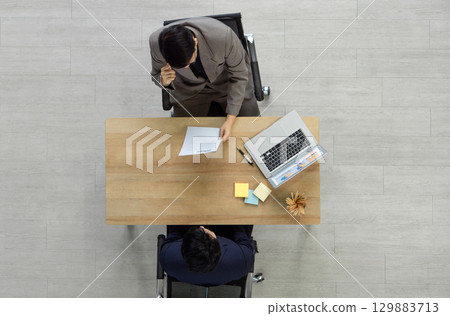 The interviewer in a suit reading candidate resume during a job interview. Top View The interviewer in a suit reading candidate resume during a job interview. Top View 129883713