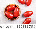 Fresh plum tomatoes, Roma tomatoes in a wooden bowl, on linen. Also known as processing or paste tomatoes, oval shaped, used for canning or producing tomato paste, because of its slender, firm nature. 129883768