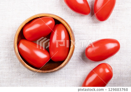 Fresh plum tomatoes, Roma tomatoes in a wooden bowl, on linen. Also known as processing or paste tomatoes, oval shaped, used for canning or producing tomato paste, because of its slender, firm nature. Fresh plum tomatoes, Roma tomatoes in a wooden bowl, on linen. Also known as processing or paste tomatoes, oval shaped, used for canning or producing tomato paste, because of its slender, firm nature. 129883768