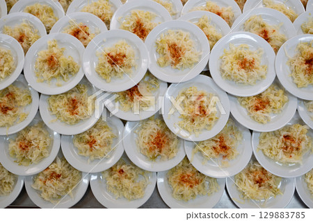 Overhead view of many plates filled with cabbage salad garnished with paprika, catering and food service concept 129883785