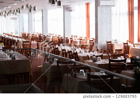Empty restaurant dining hall with arranged tables and chairs 129883793