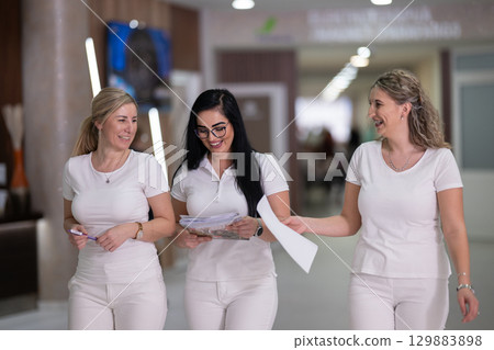 Group of smiling nurses walking in hospital hallway Group of smiling nurses walking in hospital hallway 129883898