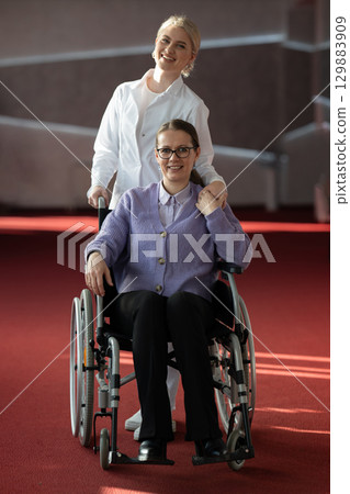 Nurse helping happy elderly woman in wheelchair 129883909