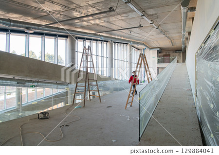 An engineer walks through the construction site, carefully inspecting the ongoing work to ensure quality control and progress in the project 129884041