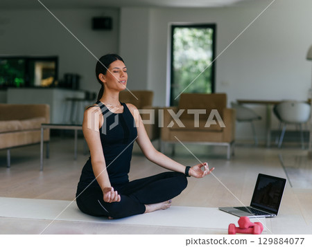 Young Beautiful Female Exercising, Stretching and Practising Yoga with Trainer via Video Call Conference in Bright Sunny House. Healthy Lifestyle, Wellbeing and Mindfulness Concept. 129884077
