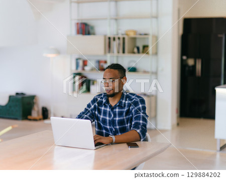 African American Man Calling While Working on Laptop African American Man Calling While Working on Laptop 129884202