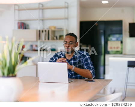 African American Man Calling While Working on Laptop 129884239