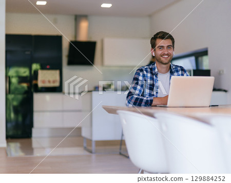Man Smiling While Working on Laptop 129884252