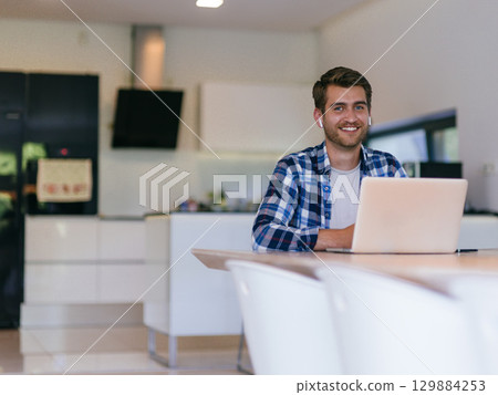 Man Smiling While Working on Laptop Man Smiling While Working on Laptop 129884253