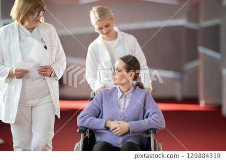 Doctor checking patients progress in wheelchair Doctor checking patients progress in wheelchair 129884319