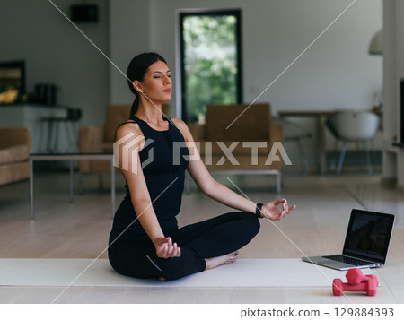 Young Beautiful Female Exercising, Stretching and Practising Yoga with Trainer via Video Call Conference in Bright Sunny House. Healthy Lifestyle, Wellbeing and Mindfulness Concept. 129884393