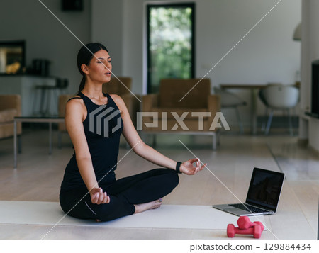 Young Beautiful Female Exercising, Stretching and Practising Yoga with Trainer via Video Call Conference in Bright Sunny House. Healthy Lifestyle, Wellbeing and Mindfulness Concept. 129884434